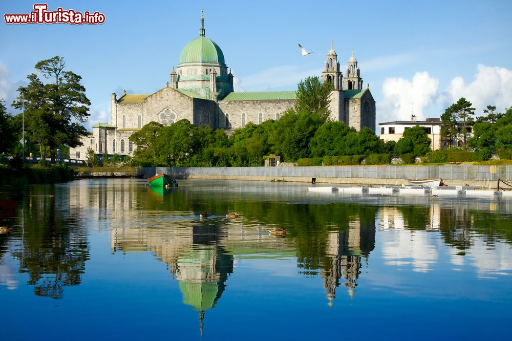Immagine La cattedrale di Galway vista dal fiume Corrib e fotografata di mattina, Irlanda. La sua forma si ispira alle chiese rinascimentali e la cupola verde spicca sulla pietra calcarea grigia con cui è costruita.