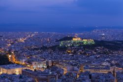 Il Partenone e l'Acropoli alla sera dominano in modo drammatico il centro di Atene (Grecia). Tutti i turisti volgono lo sguardo a questo luogo rialzato, denso di storia, e vero simbolo di ...