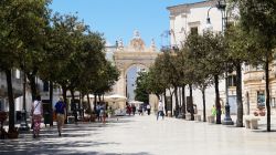 L'arco della Porta di Santo Stefano a Martina Franca, Puglia, visto da un viale. A tutto sesto, l'arco è sorretto da due paraste con capitelli compositi che reggono la trabeazione ...
