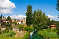 Bevagna vista dal ponte sul fiume Clitunno, Umbria. Un bel panorama con le mura cittadine e la vegetazione che la circonda.



