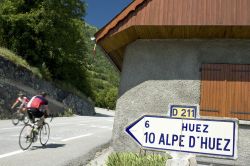 Ciclisti pedalano all'Alpe d'Huez, Francia: la strada che sale qui ha 21 tornanti, ognuno dei quali è caratterizzato da una targa a ricordo di uno dei vincitori della tappa del ...