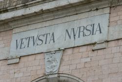 La scritta Vetusta Nursia su una porta d'ingresso lungo le mura di Norcia, Umbria - © dc975 / Shutterstock.com