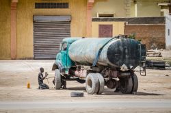 Nouakchott (Mauritania): due uomini cambiano uno pneumatico a un vecchio camion dell'acqua in una strada della città - © Fabian Plock / Shutterstock.com
