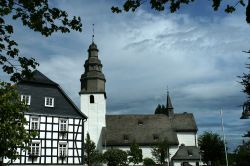 Una tipica casa con travi in legno nella cittadina di Winterberg, Germania, con a fianco la chiesa.

