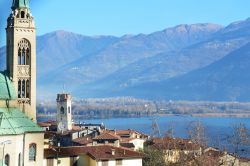 Un campanile svetta sul borgo di Lovere (Bergamo) e sul Lago d'Iseo, sullo sfondo.
