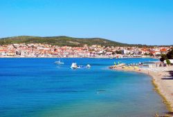 Una bella spiaggia della città di Vodice con sullo sfondo il centro abitato, Croazia. Vodizze (nome in italiano) si trova lungo la costa, adagiata in una larga baia, a circa dieci km ...
