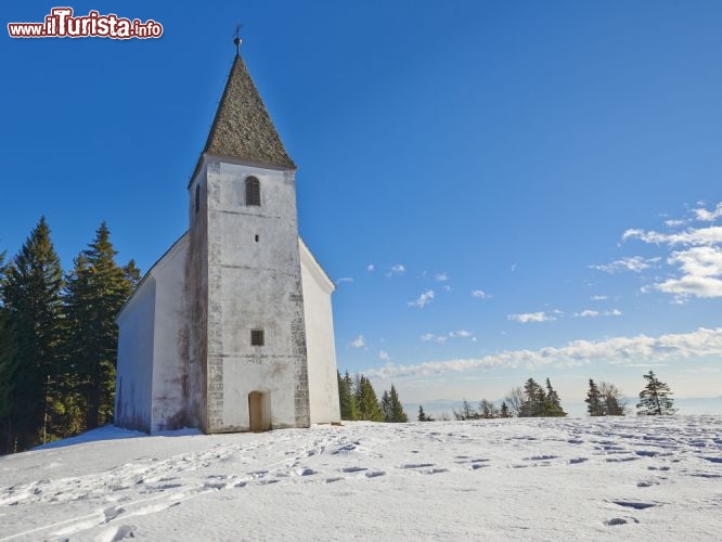 Immagine Paesaggio innevato sulla chiesa di Areh, Maribor - A 1249 metri sul livello del mare, nel cuore delle foreste verdi di Pohorje sorge la chiesetta di Areh, uno dei patrimoni storici e religiosi di tutta la Slovenia. Secondo la tradizione, la costruzione di questo edificio religioso risalirebbe alla fine del XV° secolo © onixxino / Shutterstock.com