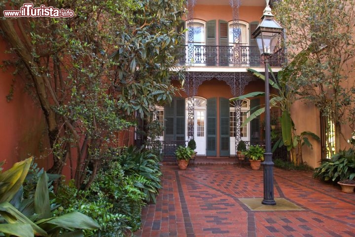 Immagine Cortile interno nel Quartiere Francese, New Orleans - Oltre ad architetture in stile coloniale, i palazzi della Big Easy sono caratterizzati da graziosi cortili interni dove a fare da protagonista è lo stretto intreccio fra intarsi in ferro battuto, persiane in legno dalle tonalità pastello e piante rigogliose che ne decorano i muri - © Natalia Bratslavsky / Shutterstock.com