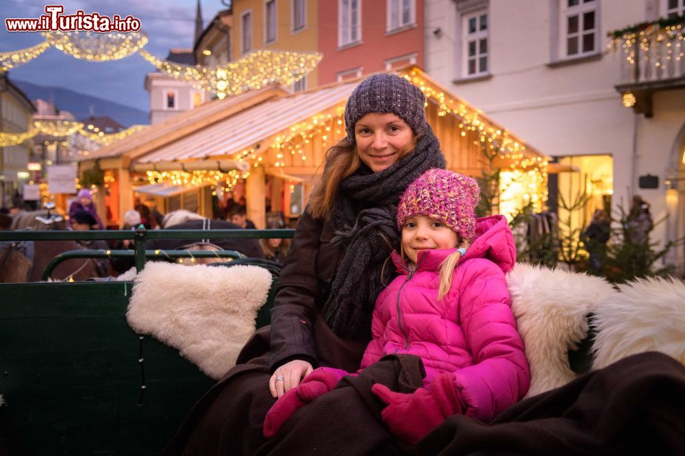 Immagine Mamma e figlia su una carrozza trainata da cavalli a Villach, Austria, durante le festività natalizie © Hannes Pacheiner