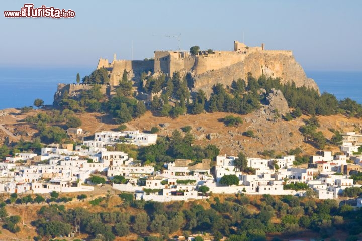 Immagine Il fascino di Lindos sull'isola di Rodi, Grecia - Il centro abitato di Lindos con alle spalle l'acropoli che sorge su una collina a precipizio sul mare alta 116 metri. La rupe ospita anche i resti del Castello dei Cavalieri, rifatto nel XIV° secolo e ricostruito successivamente all'epoca del dominio italiano fra il 1912 e il 1947 © Birute Vijeikien / Shutterstock.com