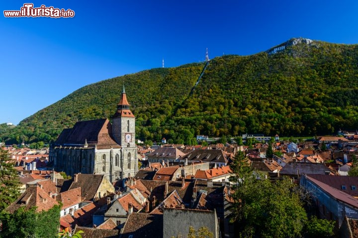 Immagine Kronstadt e Biserica Neagra, Romania - Un bel panorama sulla città vecchia di Kronstadt, antico nome di Brasov, su cui spicca l'imponente Chiesa Nera che deve il suo nome ad un terribile incendio che scoppiò nel 1689. Suggestivo il colpo d'occhio sulle colline circostanti la graziosa città rumena che sembrano quasi volerla racchiudere nel cuore della Transilvania © Christian Draghici / Shutterstock.com