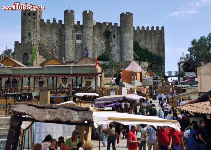 Immagine Mercato medievale a Obidos, Portogallo - Ogni anno il castello di Obidos ospita il tradizionale mercato medievale: per due settimane il borgo rievoca lo spirito dell'Europa medievale con centinaia di artisti vestiti da giocolieri, acrobati, danzatori, soldati e musicanti che animano la città. I visitatori possono passeggiare per la fiera artigianale e sperimentare le caratteristiche attività proposte dai menestrelli ma anche giochi di vario genere e tornei di cavalieri. Le taverne medievali sparse in tutta la città completano l'atmosfera del passato offrendo bevande e cibi tradizionali © Madrugada Verde / Shutterstock.com