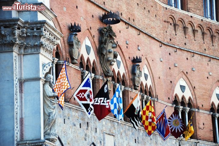 Immagine Piazza del Campo, Siena, Toscana: durante il Palio vengono esposti gli stendardi colorati delle varie contrade cittadine. Alcune contrade hanno origini antichissime, e sono storicamente rivali tra loro: ancora oggi si sfidano nella celebre corsa a cavallo, ma in passato le controversie erano dovute soprattutto a questioni territoriali  - © Irina Kovancova / Shutterstock.com