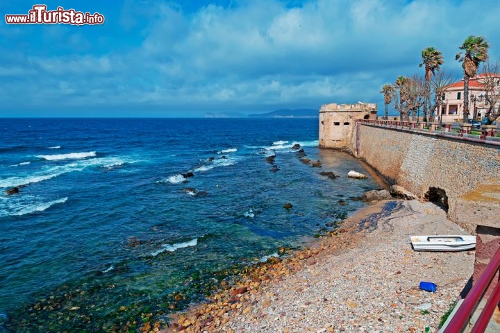 Immagine Una spiaggia di Alghero (prov. di Sassari, Sardegna) orlata dalle antiche mura del centro storico: le prime fortificazioni genovesi risalgono al XIII secolo, ma la maggior parte dei resti che vediamo oggi sono successive, del XVI secolo, quando vennero edificate per volere di Ferdinando il Cattolico  - © Gabriele Maltinti / Shutterstock.com