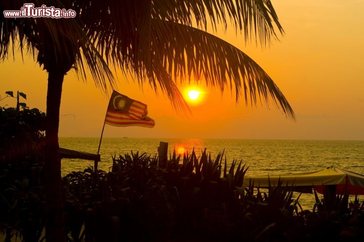 Immagine La bella spiaggia Batu Ferrenghi a Penang: una luce calda avvolge la bandiera malese (Malaysia) - ©  Shaun Robinson / Shutterstock.com