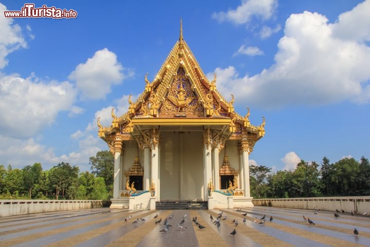 Immagine Fotografia del tempio di Wat Sa Prasan Suk, a Ubon Ratchathani - Situato circa 4 km a nord ovest dal centro della città di Ubon Ratchathani, sorge il Wat Sa Prasan Suk, conosciuto anche come Wat Ban Na Meuang. Particolarmente interessanti sono le ricche decorazioni che ricoprono interamente il tetto a pagoda e le due porte d'ingresso allo stupa. A fare da cornice all'edificio religioso vi è una vegetazione lussureggiante a testimonianza del perfetto connubio fra storia e natura © kitti suwattanakoon / Shutterstock.com