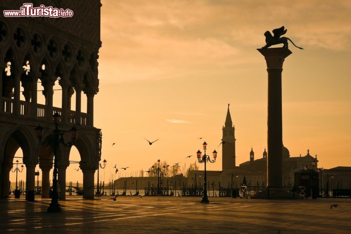 Immagine Tramonto in Piazza San Marco a Venezia. In primo piano il Palazzo Ducale e la colonna con il leone alato della Serenissima - © ErickN / Shutterstock.com