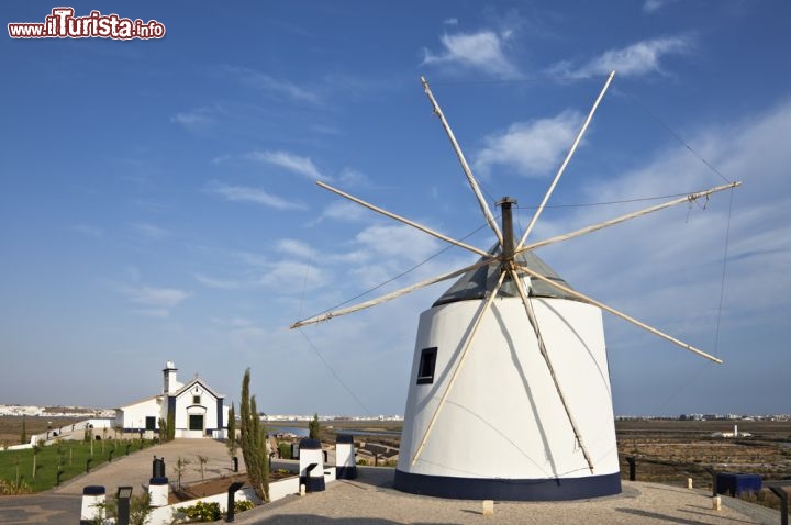 Immagine Un vecchio mulino a vento sulle colline di Castro Marim. Come le tipiche abitazioni del villaggio, anche i mulini a vento, che si stagliano sulla cima di dolci colline verdeggianti dell'Algarve, sono tinteggiati di un bianco candido che ne mette in risalto la sagoma dalle linee essenziali - © mrfotos / Shutterstock.com