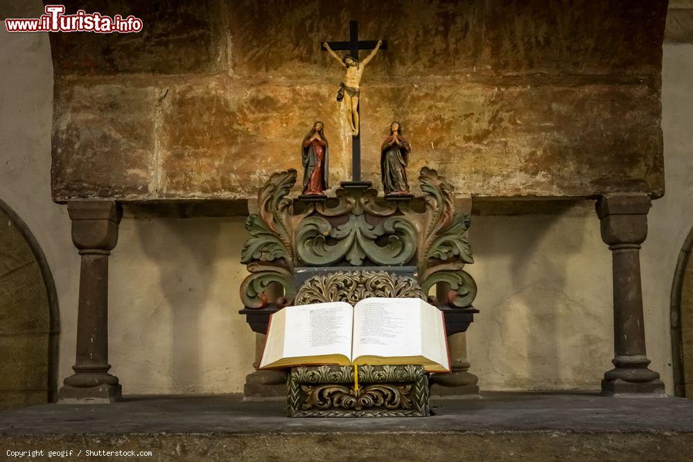 Immagine Altare in una chiesa di Goslar (Germania): la figura di Gesù scolpita nella croce sopra una copia della Bibbia aperta - © geogif / Shutterstock.com