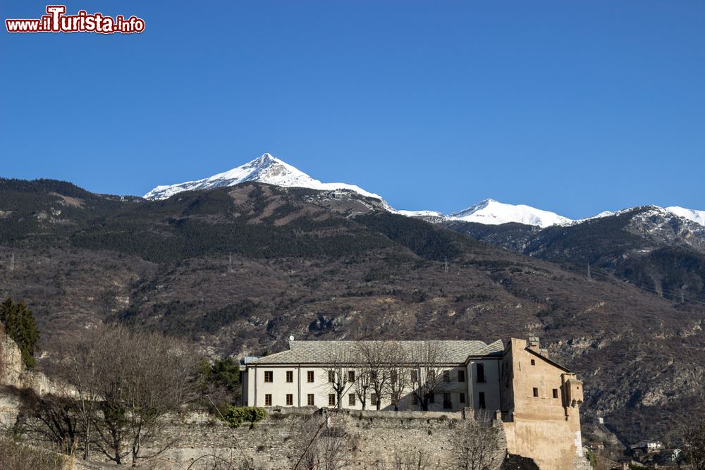 Immagine Un'antica costruzione della cittadina di Susa, Piemonte, con le cime innevate dei monti sullo sfondo.
