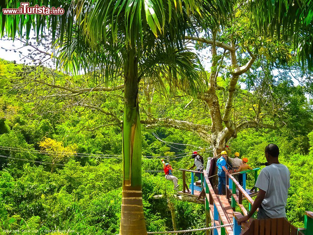 Immagine Avventura nella giungla a St. John's, Antigua e Barbuda. Una donna si appresta a lanciarsi nel vuoto fra alberi e vegetazione, imbragata solo da apposite corde di sicurezza - © Solarisys / Shutterstock.com