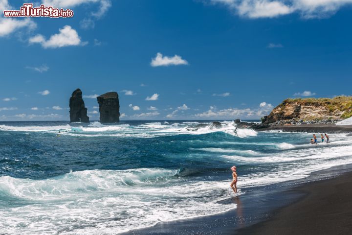 Immagine Una bambina con i piedi nell'acqua sulla spiaggia di Mosteiros a Ponta Delgada, isola di Sao Miguel (Portogallo) - © 294493358 / Shutterstock.com