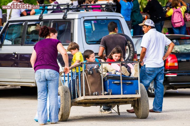 Immagine Bambini in un carretto con valigie a San José, Costa Rica. Una simpatica immagine di alcuni ragazzini seduti in un carretto assieme a borse e valigie - foto © Anton_Ivanov / Shutterstock.com