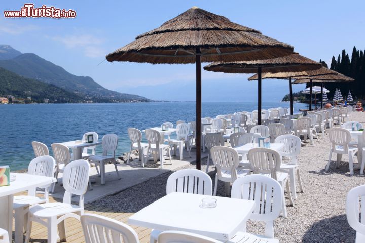 Immagine Caffè a Salò sul Lago di Garda, Lombardia. All'ombra degli ombrelloni di paglia, o sotto i raggi del sole, ci si può accomodare di fronte al lago di Garda per assaporare le specialità gastronomiche locali e ammirare l'incantevole paesaggio offerto da questo angolo della provincia di Brescia - © Rosli Othman / Shutterstock.com