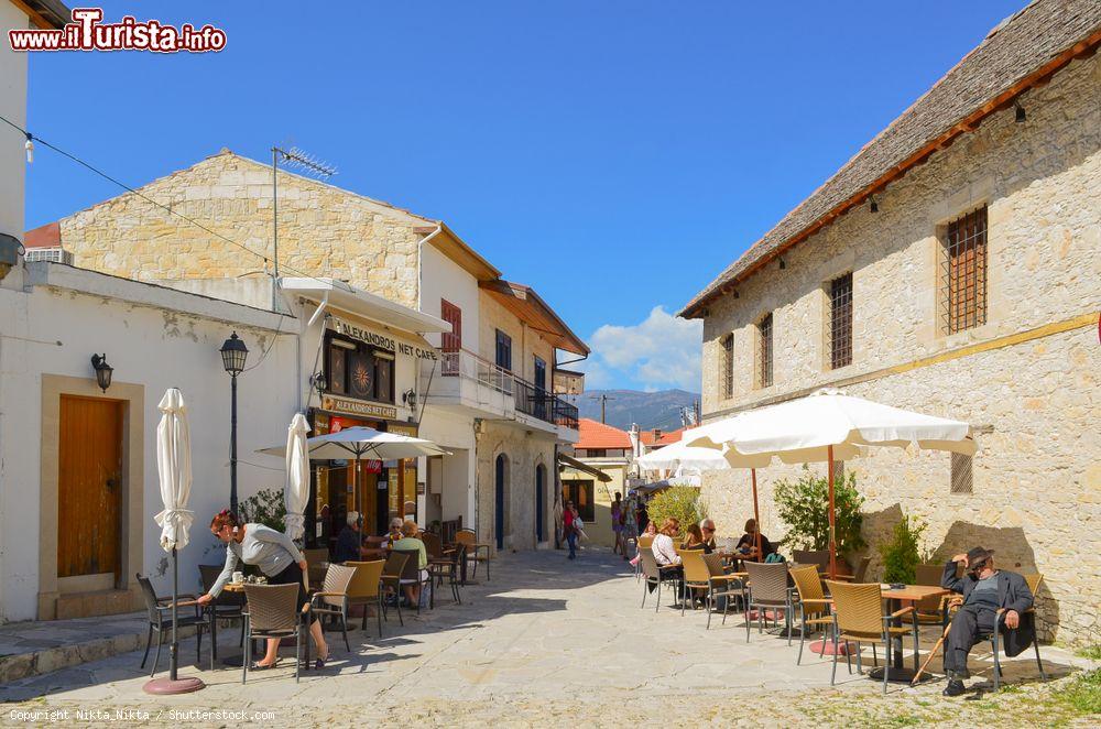 Immagine Caffè all'aperto in una stradina di Omodos, Cipro. Un uomo riposa al sole su una sedia - © Nikta_Nikta / Shutterstock.com