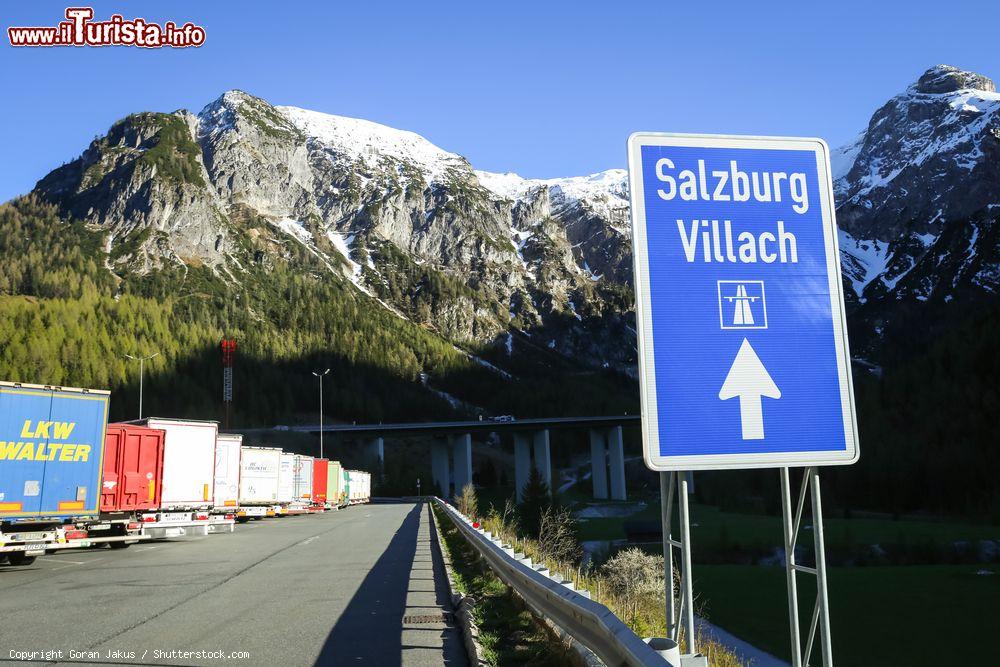 Immagine Cartello stradale in direzione di Salzburg-Villach con camion parcheggiati a lato strada, Flachau (Asutria) - © Goran Jakus / Shutterstock.com