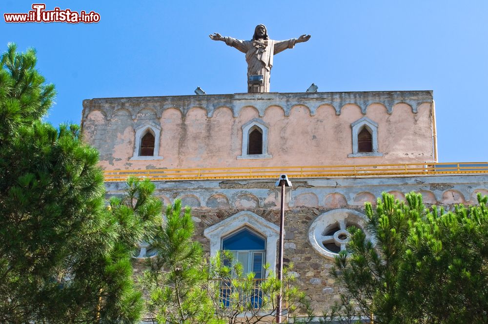 Immagine La Casa di Riposo Sacro Cuore di Gesù a Sant'Agata di Puglia. Una statua di Cristo con le braccia aperte sìinnalza sul tetto dell'edificio religioso.