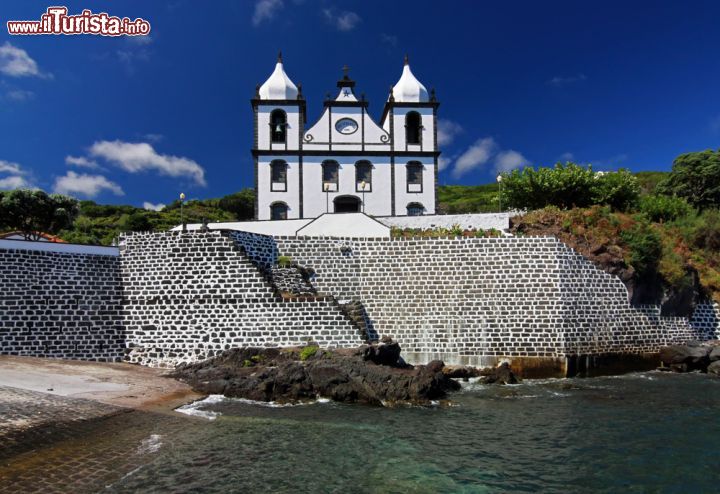 Immagine La chiesa Calheta de Nesquim, sull'isola di Pico, risplende con la sua facciata bianca cangiante che si rispecchia sulle acque dell'Oceano Atlantico - © Henner Damke / Shutterstock.com