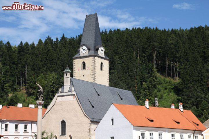 Immagine Chiesa e campanile a Rozmberk nad Vltavou, Repubblica Ceca. Cielo azzurro e vegetazione lussureggiante fanno da cornice a uno degli edifici religiosi più caratteristici di questa graziosa località del distretto di Cesky Krumlov