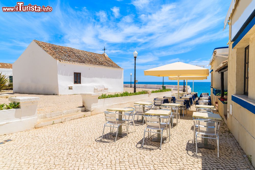 Immagine Chiesa e ristoranti sulla passeggiata costiera nella città di mare di Armacao de Pera, Portogallo. Per secoli questa è stata una località di pescatori attirati dall'abbandonza di pesce, soprattutto tonno e sardine.