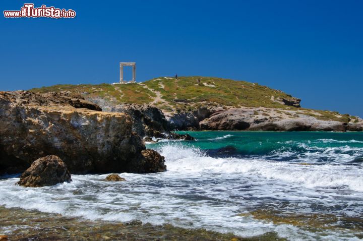 Immagine Costa a nord di Naxos, Grecia - Le acque del mar Egeo si infrangono sulla costa rocciosa e selvaggia a nord dell'isola di Naxos. Sullo sfondo la celebre porta d'ingresso, la "Portara", unici resti di un antico tempio dedicato al dio Apollo arrivati intatti sino ai giorni nostri © Albert Nowicki / Shutterstock.com