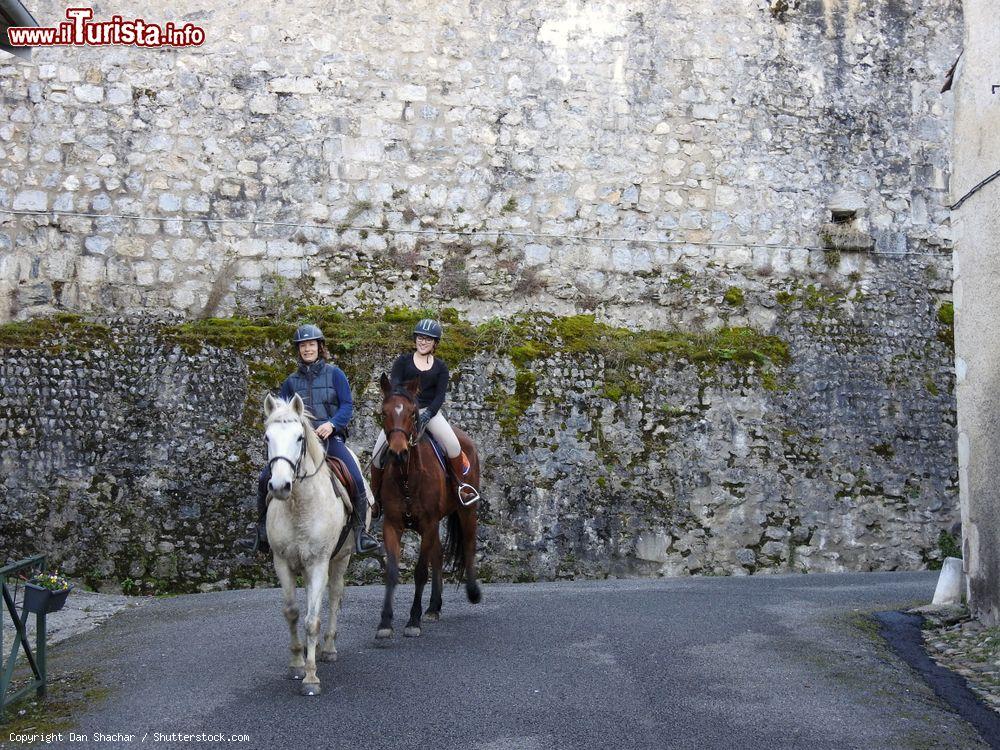 Immagine Due donne a cavallo in un vicolo di Saint-Bertrand-de-Comminges (Francia). Sullo sfondo, il muro della cattedrale, ex convento del XIX° secolo - © Dan Shachar / Shutterstock.com