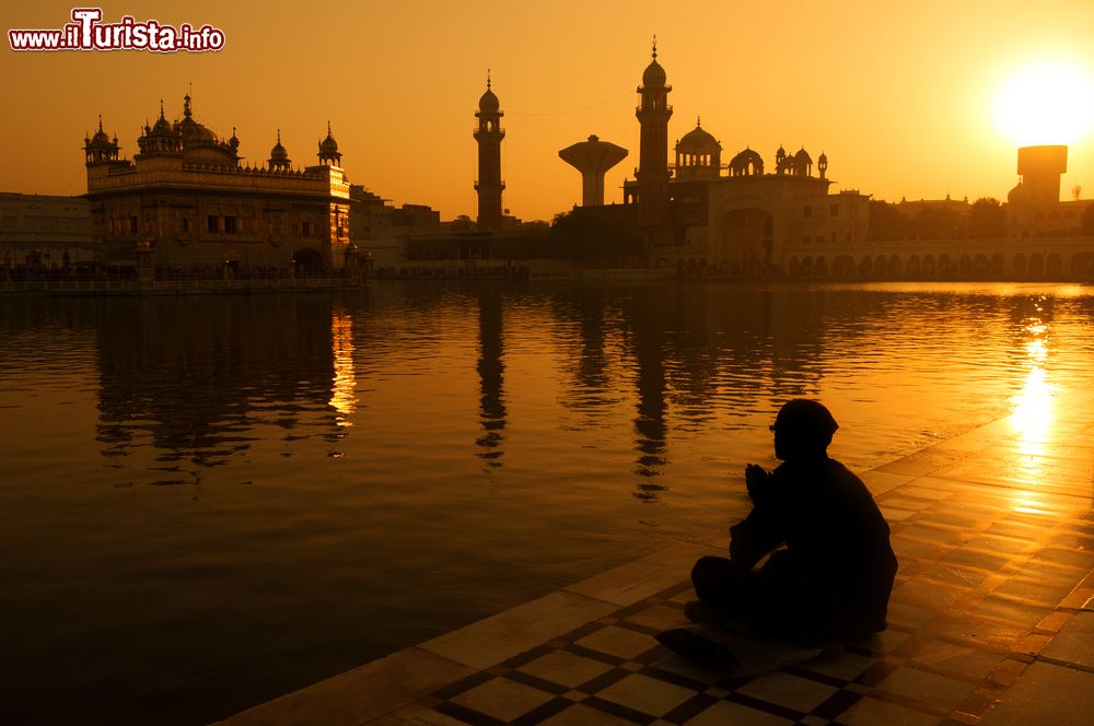 Immagine Fedeli sikh seduti al tramonto lungo la piscina sacra del Tempio d'oro a Amritsar, Punjab, India.