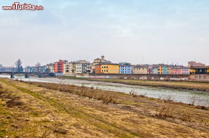 Immagine Paesaggio autunnale della Parma, l'affluente del Po che porta il nome della città - la Parma, importante torrente affluente del Po, attraversa l'omonima città e la divide in due. Il paesaggio autunnale del lungo fiume è particolarmente suggestivo dal punto di vista dei colori. Davvero interessante è infatti il contrasto tra il paesaggio spoglio dei margini del torrente e i colori vivaci e sgargianti delle case del centro città. - © Eddy Galeotti / Shutterstock.com