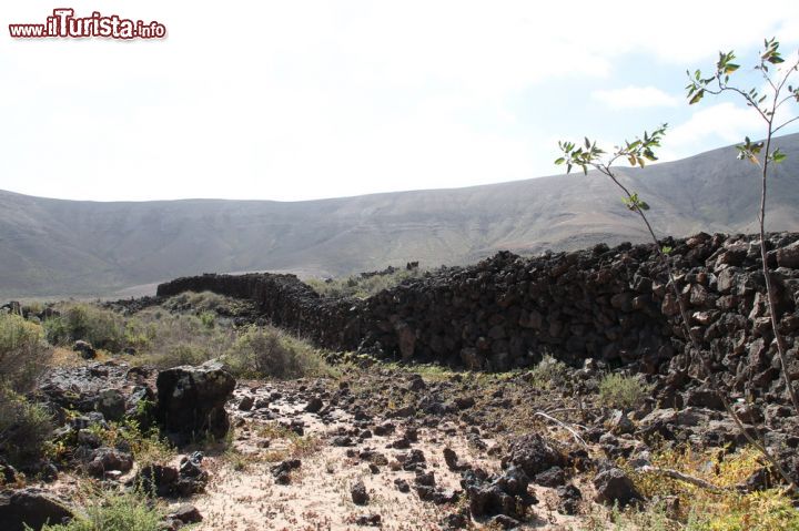 Immagine La natura incontaminata del villaggio preistorico di Fuerteventura (Spagna) - In moltissime zone appartenenti al villaggio preistorico di Fuerteventura il terreno si presenta rossiccio, arido e ricorda in tutto e per tutto la storia lontana. Alcune zone però richiamano anche agli usi e costumi dei popoli berberi che si susseguirono nel corso dell'evoluzione. Proprio come nel caso di questa immagine dove i fortini in pietra che costeggiano il panorama sono rimasti intatti.