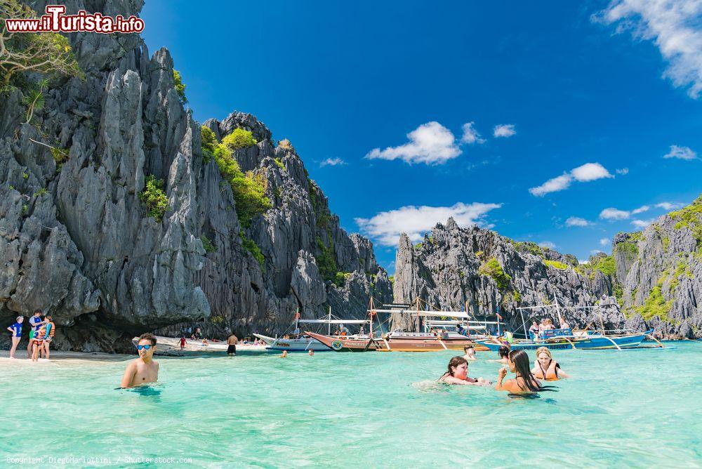 Immagine Gente in relax nelle acque tropicali di Palawan, isola delle Filippine. Sullo sfondo, le tipiche barche in legno - © DiegoMariottini / Shutterstock.com