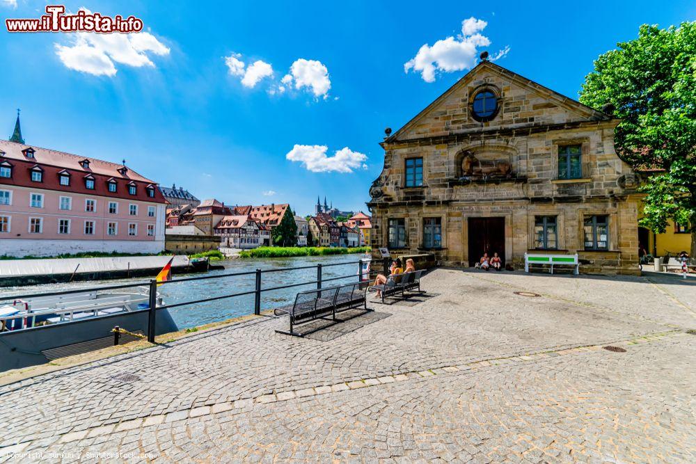 Immagine Gente seduta su una panchina lungo il fiume a Bamberga, Germania - © sunfun / Shutterstock.com