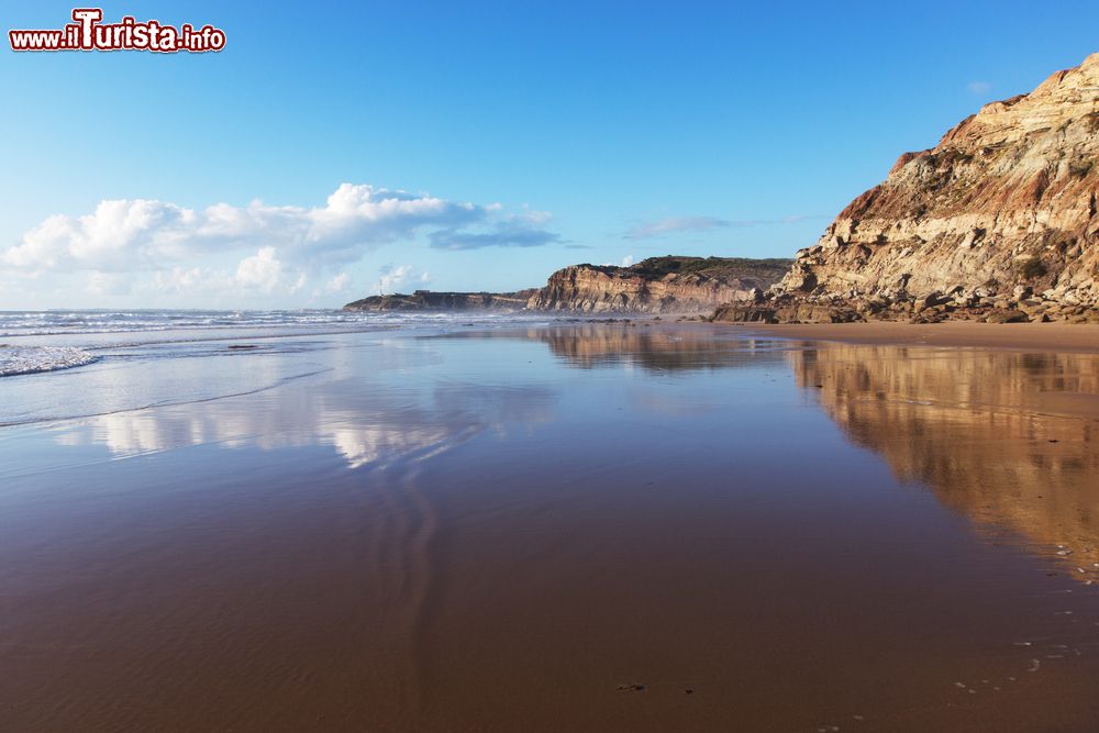 Immagine I riflessi delle montagne sull'acqua limpida della spiaggia di Areia Branca, Portogallo.