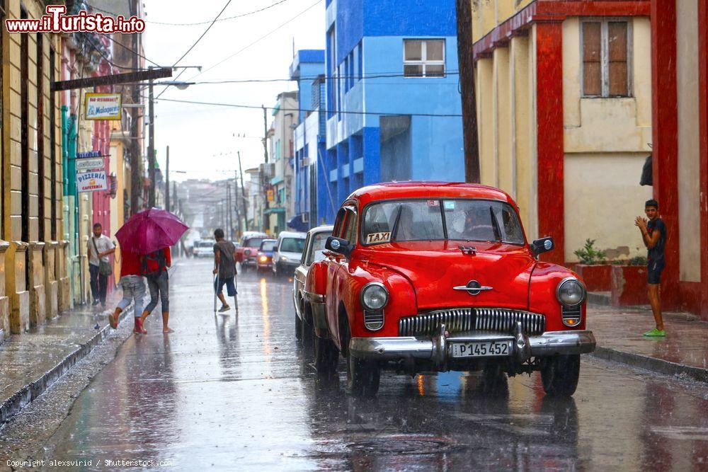 Immagine Iconico taxi rosso si riflette sulla strada bagnata di Holguin, Cuba. Siamo nella quarta più vasta città di Cuba - © alexsvirid / Shutterstock.com