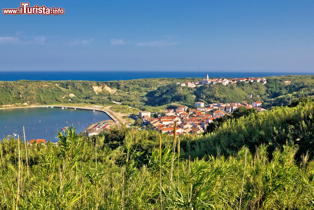 Immagine Il paesino sull'isola di Susak, in Croazia. Qui vivono in pianta stabile circa 180 persone, ma in estate l'isola raggiunge quasi i 2000 abitanti. Susak è rimasta per lungo tempo disabitata, cioè nel lasso di tempo intercorrente fra la caduta dell’Impero Romano d’Occidente all’XI secolo, quando giunsero i Benedettini. L’impulso cristiano diede adito a costruzioni capaci di regolare in qualche modo l’esistenza nelle desertiche aree isolane, così oggi molte di queste risultano ampiamente percorribili, altre visitabili per la presenza di attrattive ed edifici interessanti sotto il profilo artistico. Abbiamo la Scalinata di 150 gradini che collega la parte bassa e la parte alta di Susak, il faro eretto nel 1885 e ora pienamente automatizzato, l’ex avamposto di guardia protetto da alte mura utilizzato a metà ‘900 dalle milizie jugoslave, poi abbandonato e riutilizzato come ricovero per le pecore, la settecentesca Parrocchiale di San Nicola e, infine, il cimitero con la Cappella della Santa Madre Addolorata poco distante dalla Cappella dell’Annunciazione.