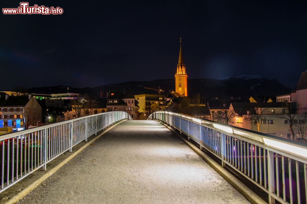 Immagine Il ponte sul fiume Drava fotografato di notte a Villach, Austria. Sullo sfondo, la torre campanaria illuminata.