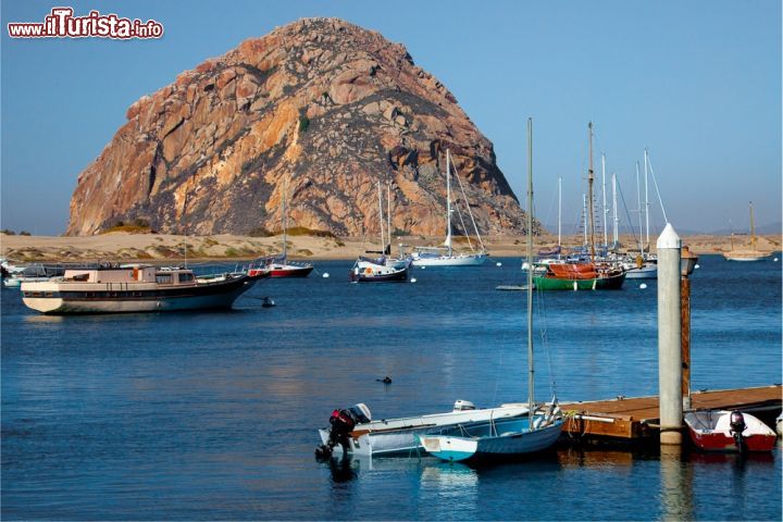 Immagine Il porto di Morro Bay, California, con il Morro Rock sullo sfondo. Si tratta di un cono vulcanico che s'innalza per 176 metri e che si trova all'entrata dell'area portuale. E' collegato alla spiaggia da una strada rialzata - © Leifr / Shutterstock.com