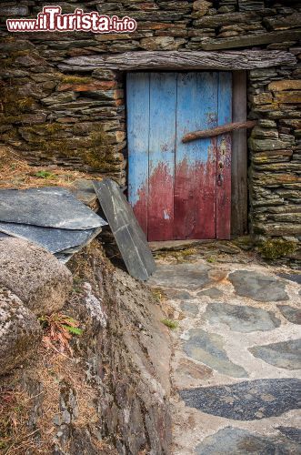 Immagine Ingresso di un vecchio edificio a Piodao, Portogallo - Una stradina lastricata porta a questa abitazione in pietra a cui si accede tramite una porta in legno azzurra © Carlos Caetano / Shutterstock.com