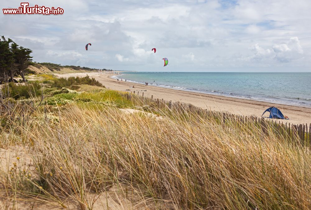 Immagine Kite surfing su una spiaggia deserta dell'isola di Ré, Francia. Dune di sabbia ricoperte di erba caratterizzano questo lembo di terra.