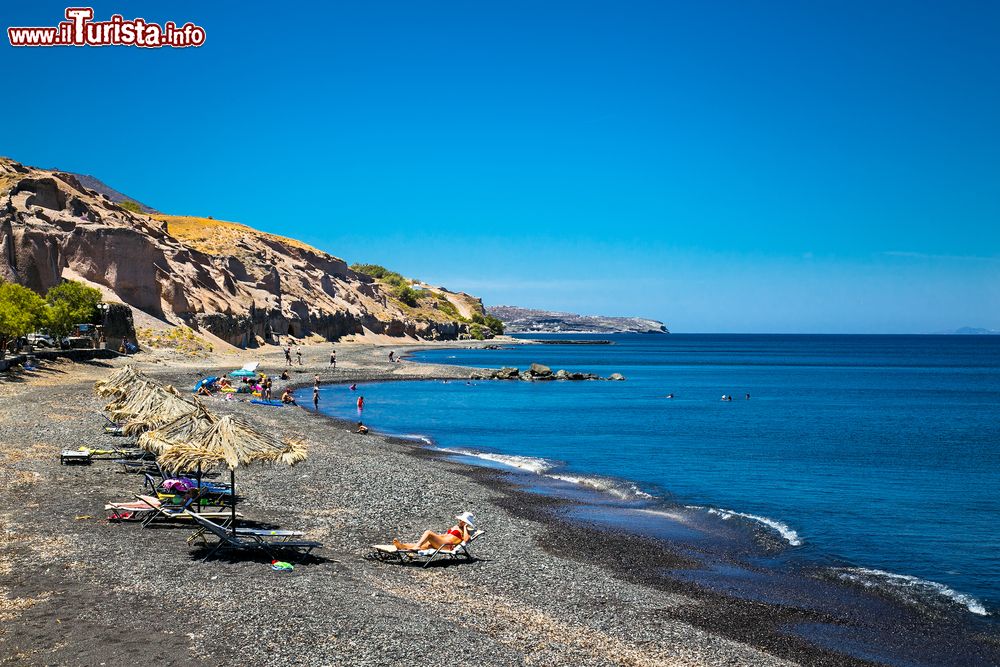 Immagine La spiaggia nera di Karterados a Santorini, in Grecia. Ciottoli neri rendono questo tratto di spiaggia uno dei più suggestivi e frequentati dai turisti. Il mare con basso fondale permette di nuotare a pochi passi dalla riva.