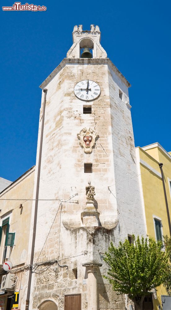 Immagine La torre dell'orologio a Monopoli, Puglia. Su piazza Garibaldi, nota anche come piazza dei Mercanti per via della presenza delle botteghe, si affaccia la torre civica con il campanile i cui rintocchi, in passato, erano segnale di pericolo e adunanze. Alla base la torre ingloba la "colonna infame" a cui erano legati coloro che dovevano subire una pubblica punizione.